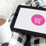 Une tablette connectée à un site e-commerce est posée sur les genoux d'une commerçante.
