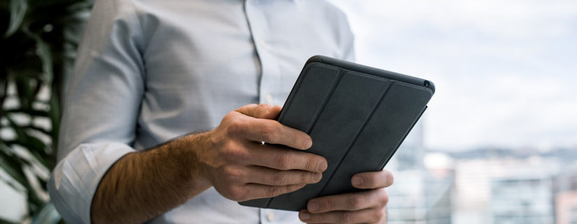 Un commerçant a une tablette entre les mains. Il utilise son logiciel de caisse iPad.