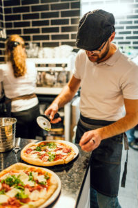 Dans la cuisine d’une pizzeria, un pizzaiolo à l’œuvre.