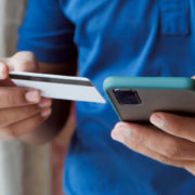 Un client, carte bancaire et iPhone en mains, effectue un achat sur Internet qui sera géré par une caisse enregistreuse en ligne.