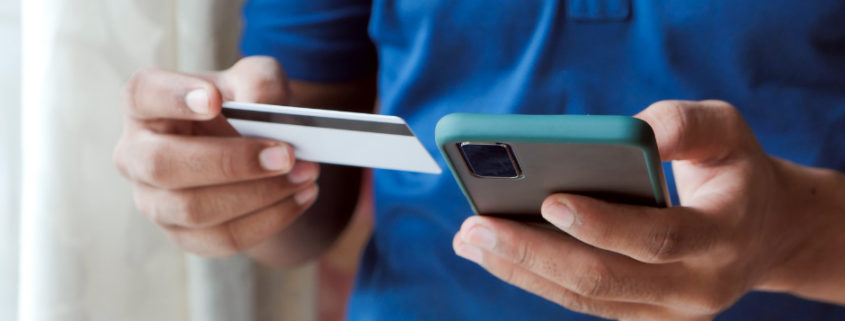 Un client, carte bancaire et iPhone en mains, effectue un achat sur Internet qui sera géré par une caisse enregistreuse en ligne.