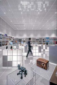 Homme un peu flou marche dans l'espace blanc ultra moderne d'un magasin. Sur le comptoir en forme de cube apparaît le matériel d'un logiciel de caisse concept store.