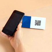 Main qui tient un smartphone pour lire un QR code sur une étiquette générée par un logiciel de caisse QR codes.