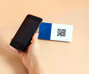 Main qui tient un smartphone pour lire un QR code sur une étiquette générée par un logiciel de caisse QR codes.