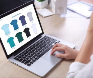 Une commerçante gère sur écran son catalogue produits et sélectionne les coloris disponibles d’un tee-shirt à vendre.