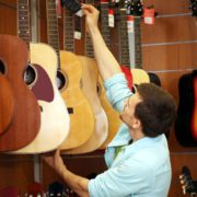 Jeune homme choisissant une guitare dans le rayon d’un magasin utilisant un logiciel de caisse magasin matériel de musique.