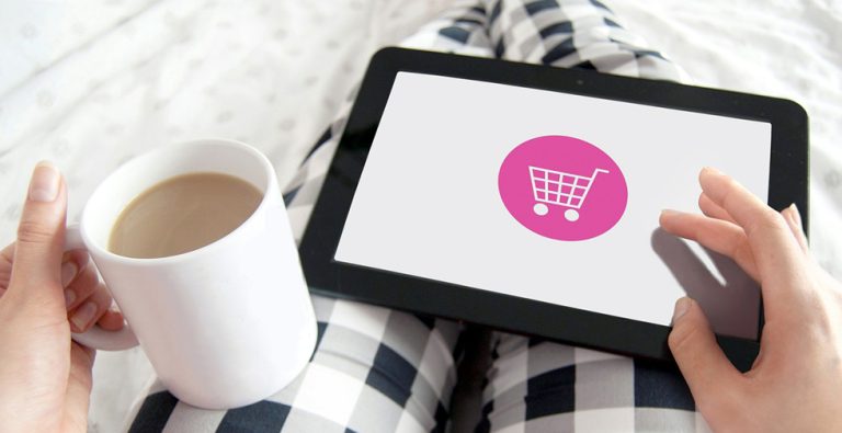 Une tablette connectée à un site e-commerce est posée sur les genoux d'une commerçante.