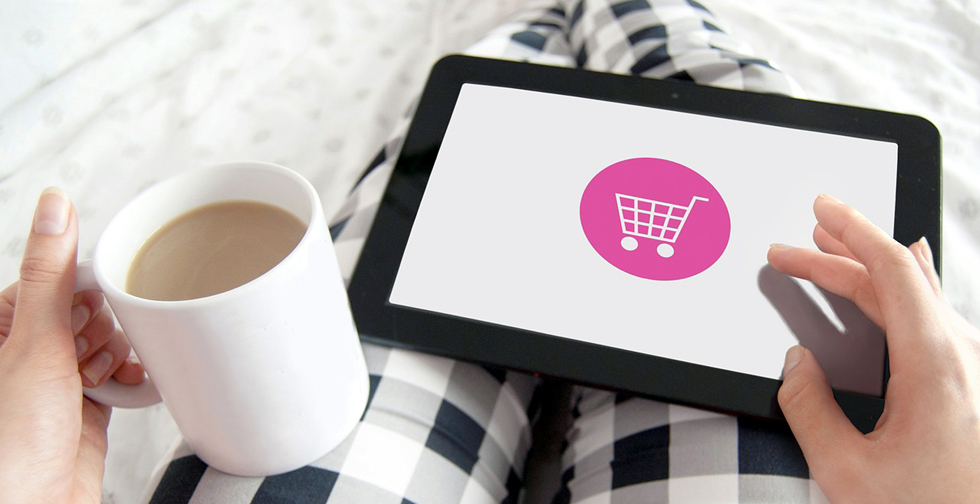 Une tablette connectée à un site e-commerce est posée sur les genoux d'une commerçante.