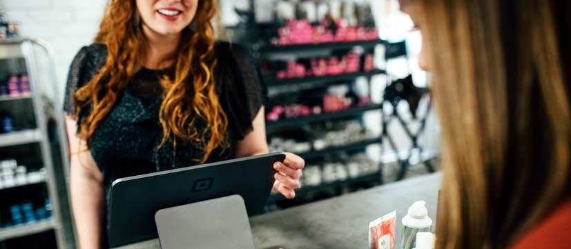 Commerçante utilisant une bonne solution de gestion de caisse, souriante devant une cliente.