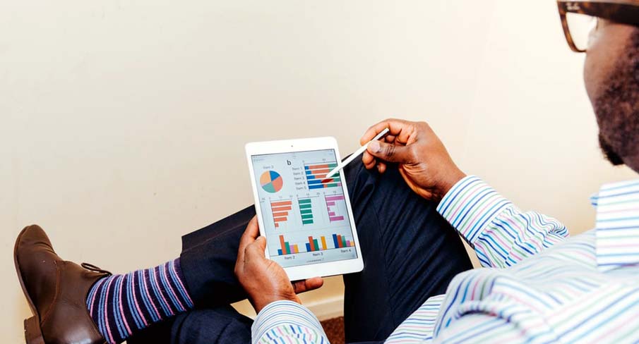 Un commerçant, tranquillement assis, consulte sur une tablette les statistiques de son site e-commerce et de son magasin.