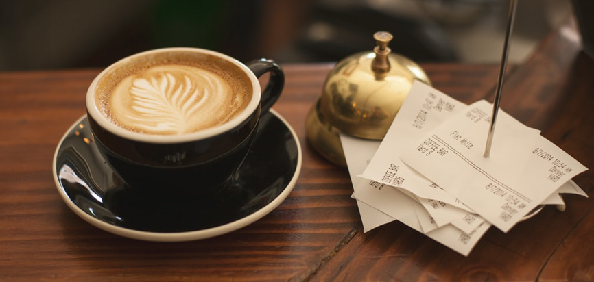 Tickets de caisse imprimés et empilés près d'une tasse de café.
