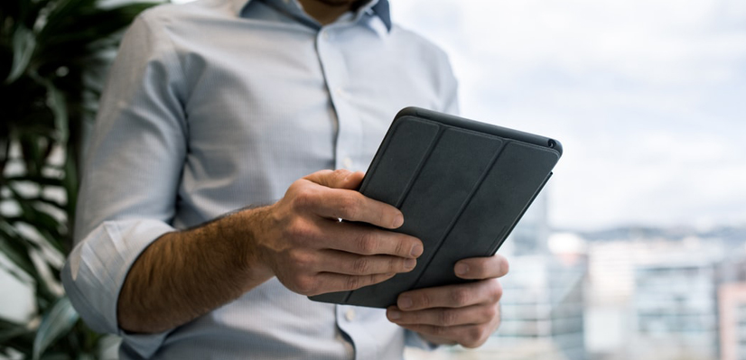 Un commerçant a une tablette entre les mains. Il utilise son logiciel de caisse iPad.