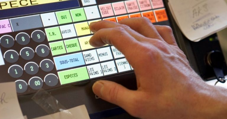 La main d’un homme essayant de trafiquer une caisse enregistreuse.