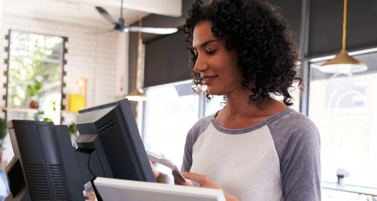 Une jeune commerçante, dans son magasin, utilise sa caisse enregistreuse nouvelle génération.