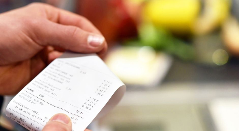 Ticket de caisse entre les mains d'un consommateur qui le vérifie.