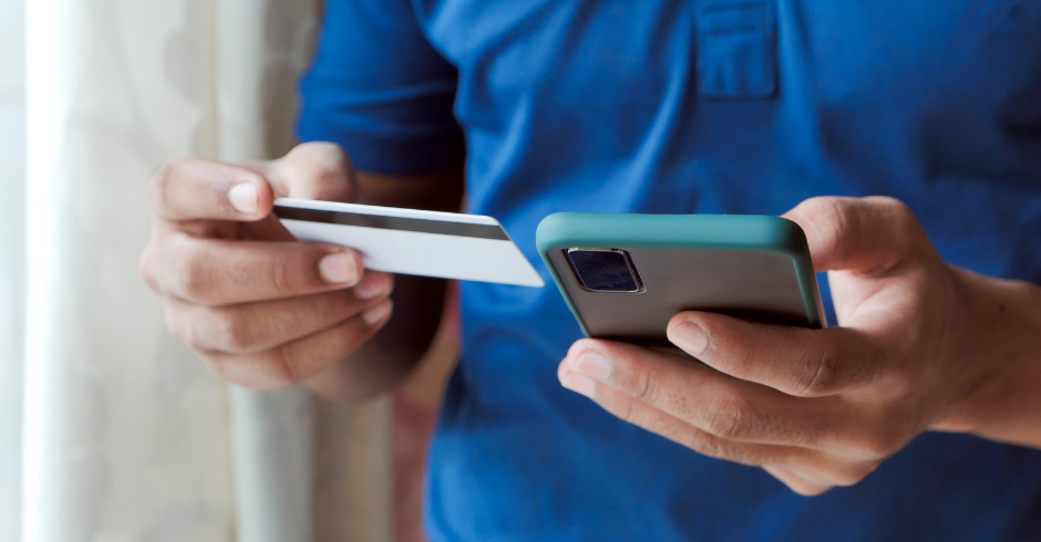 Un client, carte bancaire et iPhone en mains, effectue un achat sur Internet qui sera géré par une caisse enregistreuse en ligne.