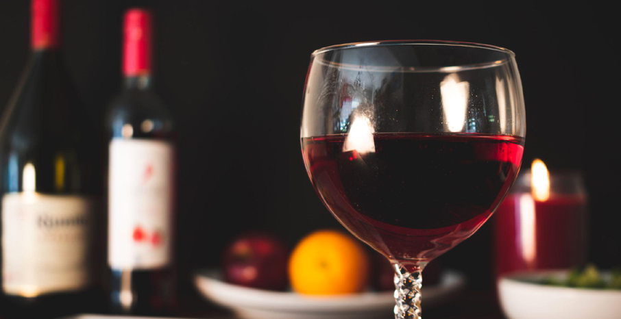 Beau verre de vin sur une table, avec deux bouteilles en arrière-plan.