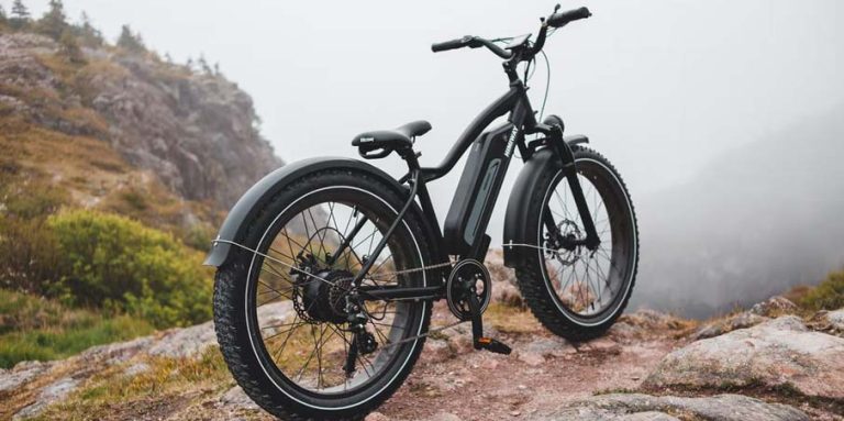 Vélo électrique noir reposant sur sa béquille en haut d'une colline.