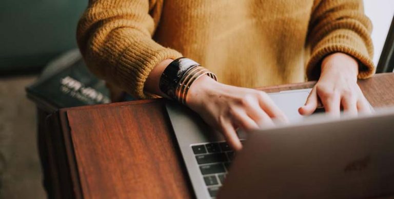 Commerçante utilisant le logiciel de caisse WooCommerce KerAwen derrière son ordinateur portable.