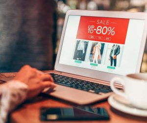 Sur un ordinateur portable, un homme regarde des vêtements sur un site de vente.