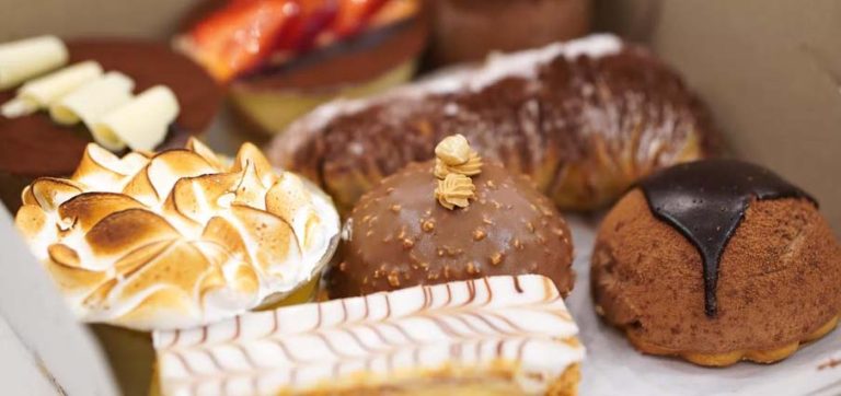 Gros plan sur une dizaine de pâtisseries variées : millefeuille, tarte au citron et à la fraise...