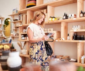 Une jeune femme souriante examine un article dans un magasin de produits de beauté.