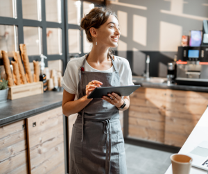 Une commerçante souriante avec, entre ses mains, une tablette lui servant aussi de caisse enregistreuse !