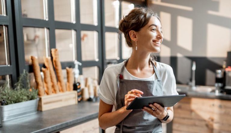 Commerçante, tout sourire, avec entre les mains une tablette équipée d’un logiciel de caisse iPad.