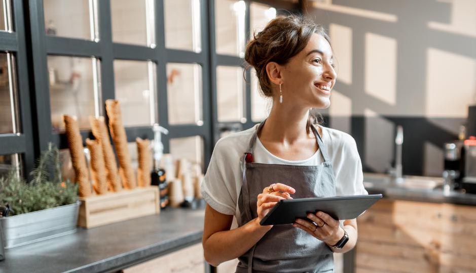 Commerçante, tout sourire, avec entre les mains une tablette équipée d’un logiciel de caisse iPad.