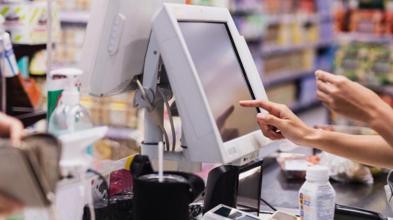 Main d’une commerçante. Son doigt enregistre des achats en appuyant sur un écran tactile. Elle sait apparemment très bien comment fonctionne un logiciel de caisse.