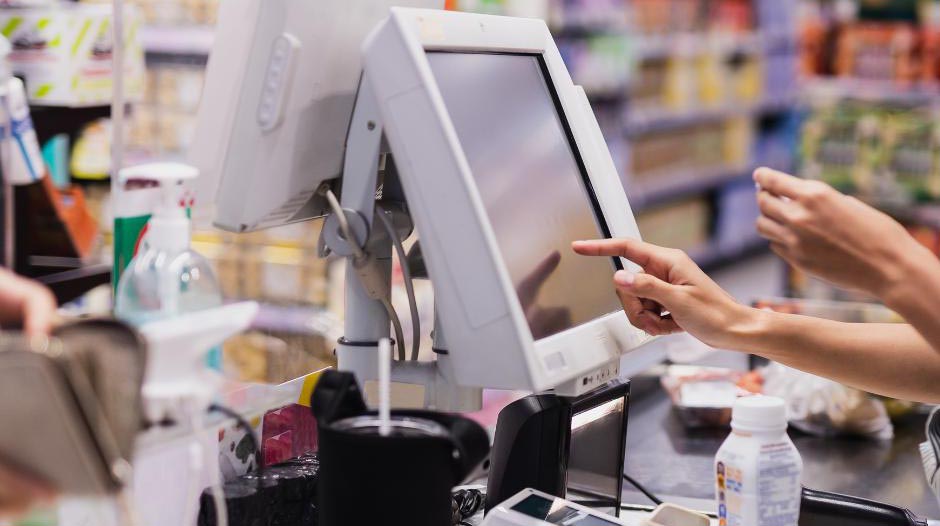 Main d’une commerçante. Son doigt enregistre des achats en appuyant sur un écran tactile. Elle sait apparemment très bien comment fonctionne un logiciel de caisse.