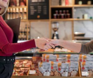 Affaire conclue : deux femmes se serrent la main devant le présentoir d’une chocolaterie.