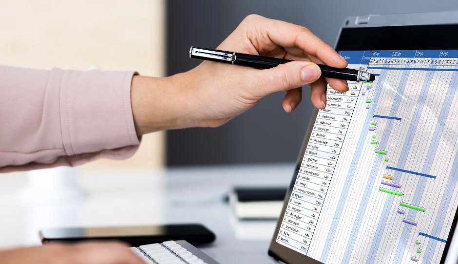 Main d’un homme travaillant sur écran avec un logiciel de gestion.