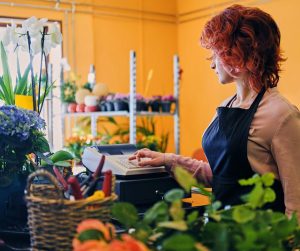 Dans une jardinerie lumineuse, une jeune femme utilise une caisse enregistreuse.