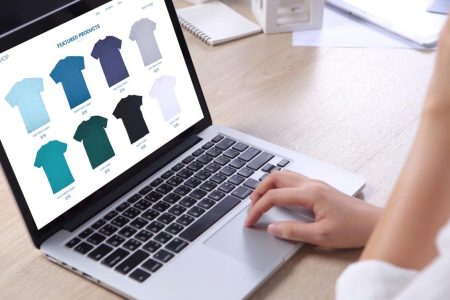 Une commerçante gère sur écran son catalogue produits et sélectionne les coloris disponibles d’un tee-shirt à vendre.